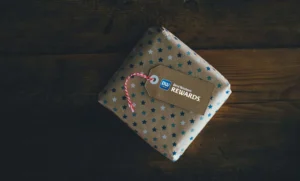 Un pacchetto regalo con carta ricoperta di stelline bianche e blu e un bigliettino con il logo best western rewards