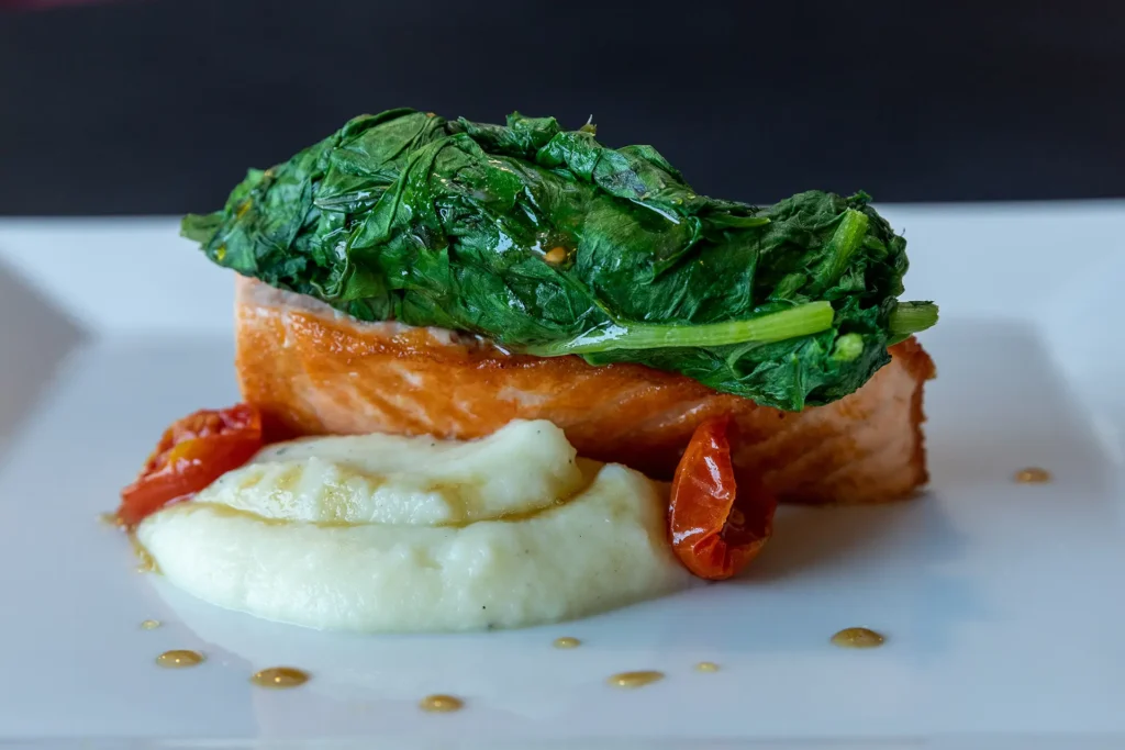 Un trancio di salmone con degli spinaci e una crema di patate