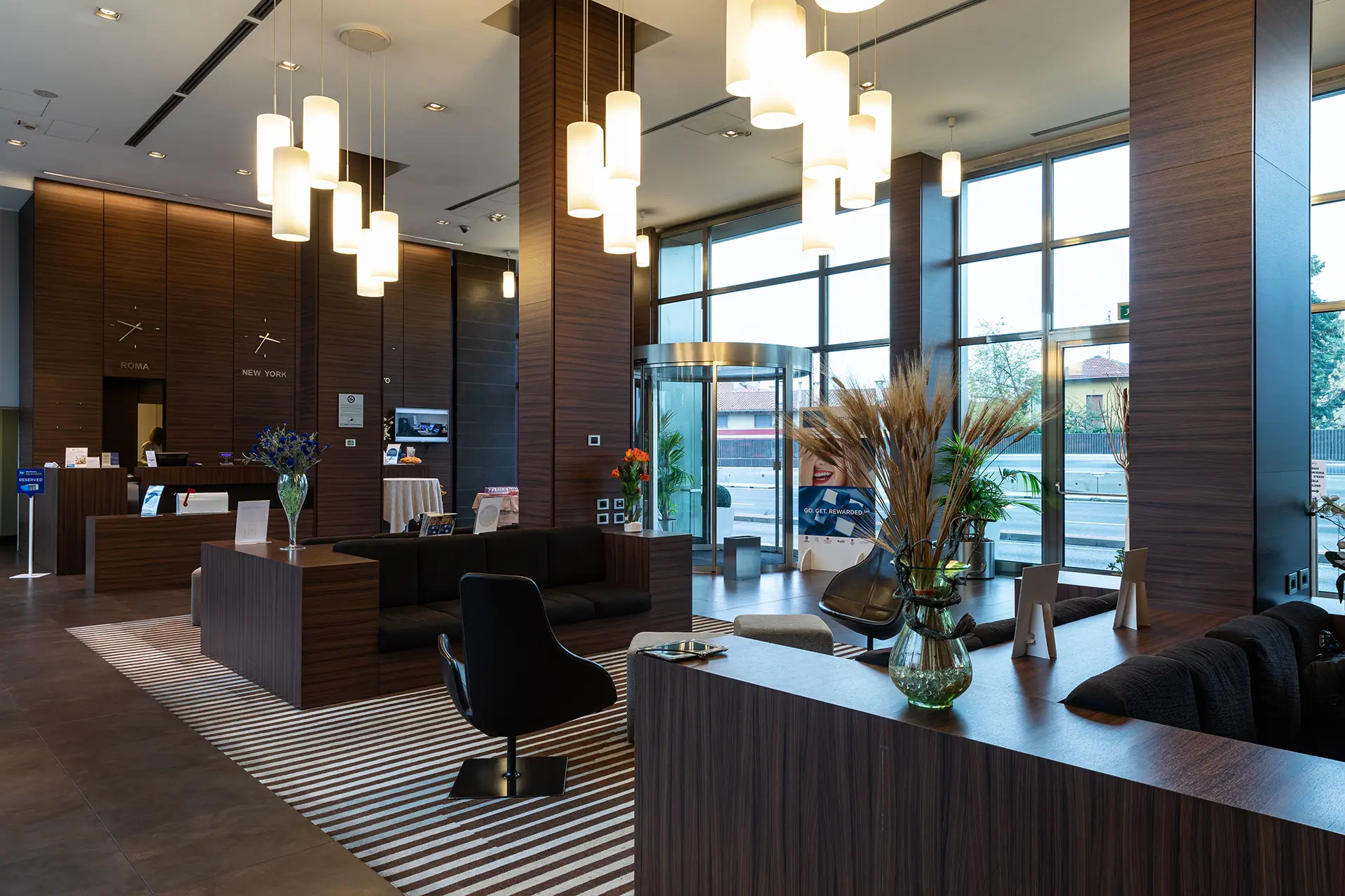 La lobby dell'hotel, dallo stile moderno, con grandi vetrate, legno e tappeti e poltrone di design