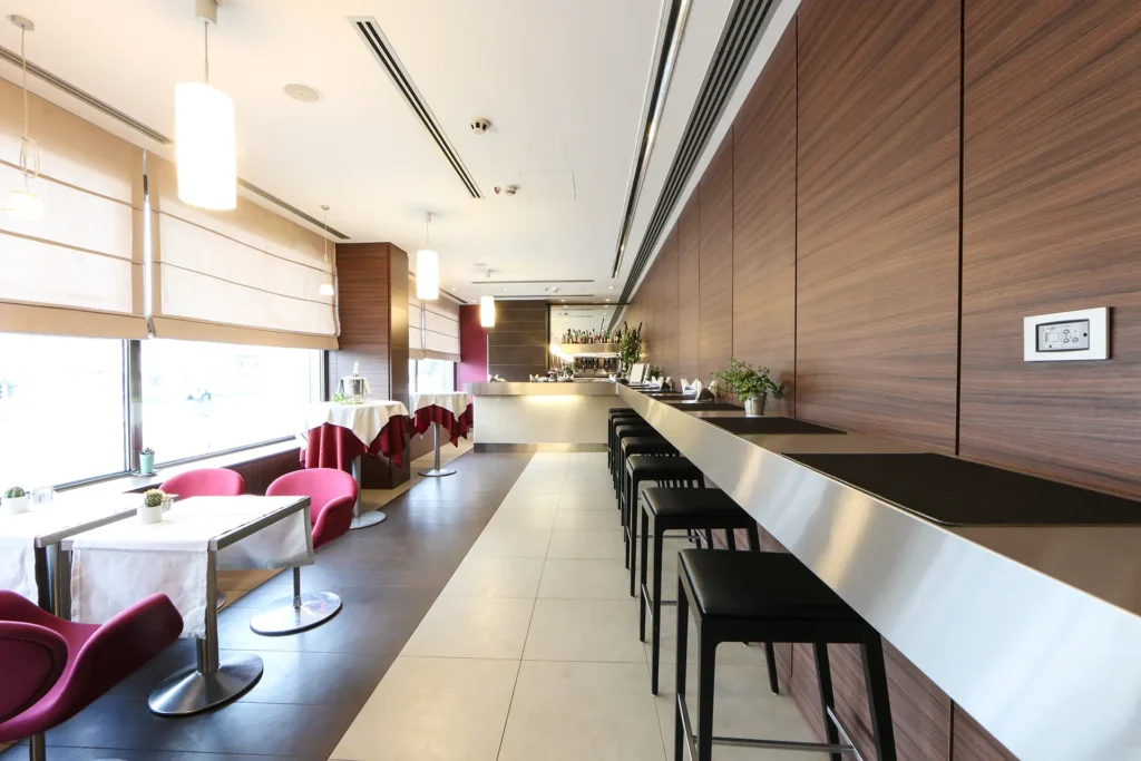 Vista del ristorante dell'hotel, con i tavoli apparecchiati in fila, lungo le vetrate